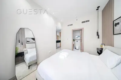 a white bedroom with a white bed and a mirror at Azizi Greenfield, Meydan Dubai in Dubai