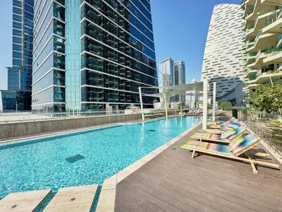 a swimming pool with lounge chairs and buildings at Premium 2BR Apartment at Urban Oasis, Business Bay in Dubai