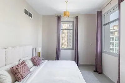 a white bedroom with a bed and a window at Bright 2BR Marina View with Balcony in Dubai