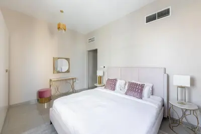 a white bedroom with a large white bed with purple pillows at Bright 2BR Marina View with Balcony in Dubai