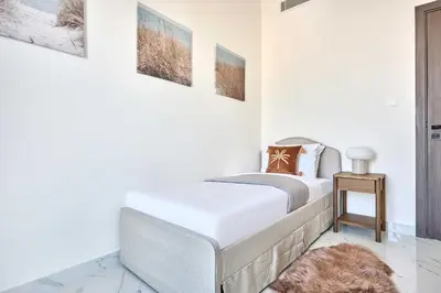 a white bedroom with a bed and a table at Frank Porter - Adhara Star in Dubai