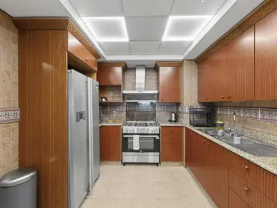 a large kitchen with wooden cabinets and a white refrigerator at DVH Al Basri Palm Beachfront 2BR Full Sea Views in Dubai