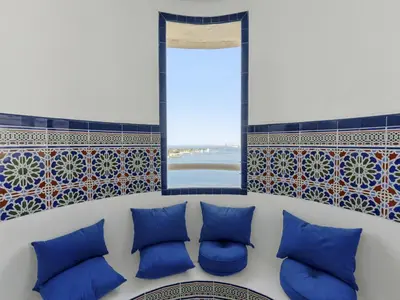 a bench with blue pillows in a room with a window at DVH Al Basri Palm Beachfront 2BR Full Sea Views in Dubai