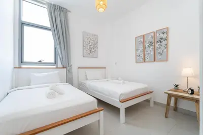 two beds in a white room with a window at StayShort - Cozy 2 Bedroom Retreat in Dubai South Close to Expo 2020 in Dubai Marina