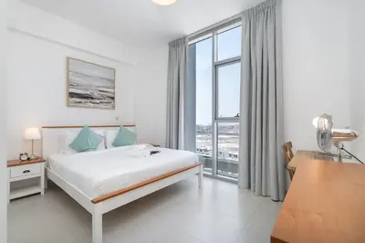 a white bedroom with a bed and a large window at StayShort - Cozy 2 Bedroom Retreat in Dubai South Close to Expo 2020 in Dubai Marina