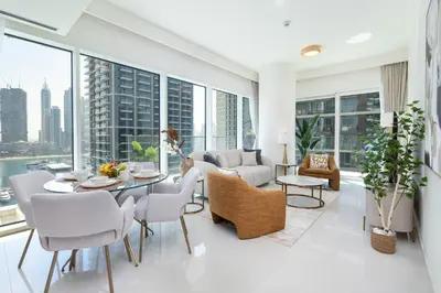 a living room with white furniture and large windows at Beachfront Luxury 1BR with Private Beach, Marina & Sea Views in Dubai