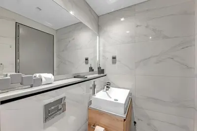 a white bathroom with a sink and a mirror at Chic Studio Steps to Dubai Mall with Infinity Pool in Dubai