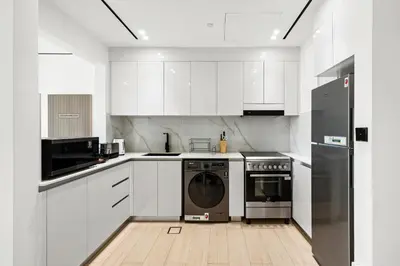 a white kitchen with white cabinets and a dishwasher at Stylish 1-Bedroom Apartment in JVC Dubai in Dubai