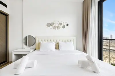 a bedroom with a large white bed with a window at Stylish 1-Bedroom Apartment in JVC Dubai in Dubai