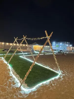 a field with lights in the sand at night at dubai camp in ‘Ūd al Bayḑāʼ