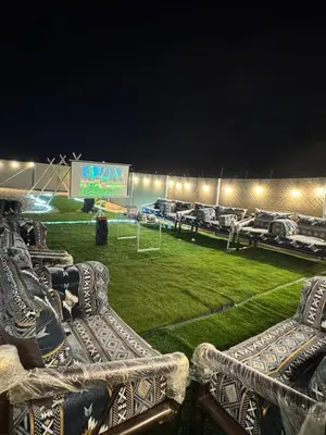 a field with chairs and a soccer field at night at dubai camp in ‘Ūd al Bayḑāʼ