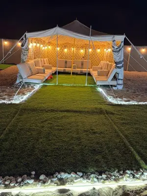 a tent with couches in a field at night at dubai camp in ‘Ūd al Bayḑāʼ