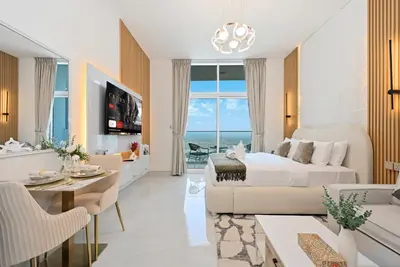 a living room with a bed and a dining room at Luxury studio Near Miracle Garden with Gym & Pool in Dubai