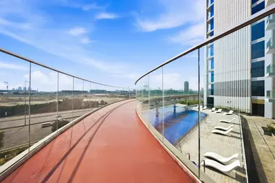 a glass walkway in a building with a pool at Luxury studio Near Miracle Garden with Gym & Pool in Dubai