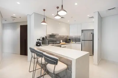 a kitchen with a counter and some stools at Comfortable 2BR Near Downtown by Czechin in Dubai
