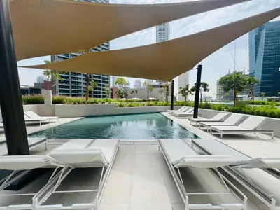 a swimming pool with lounge chairs and an umbrella at Curated High-Floor 1BR Water View Peninsula 1 in Dubai