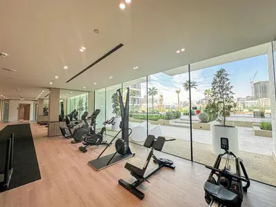 a gym with a lot of treadmills and exercise bikes at WelHome - Urban Comfort Studio in JVC in Dubai