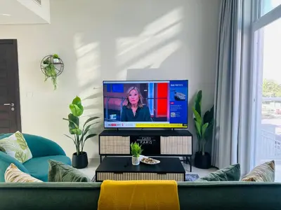 a living room with a couch and a flat screen tv at 1 BR luxury flat Damac hills2 in ‘Ūd al Bayḑāʼ