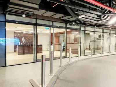 a large glass building with a man walking in front of a store at Vogue Marina Gate near JBR Beach and Marina Mall, One Bedroom Apartment with Balcony and city skyline view, Access to all Amenities in Dubai