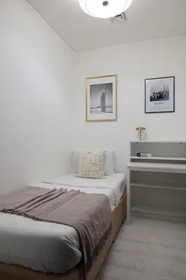 a white bedroom with a bed and a piano at Gentle brutalism apartments on Sobha Hartland 3BR in Dubai