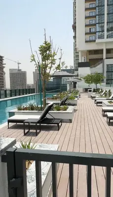 a row of chaise lounges and a pool on a building at Gentle brutalism apartments on Sobha Hartland 3BR in Dubai