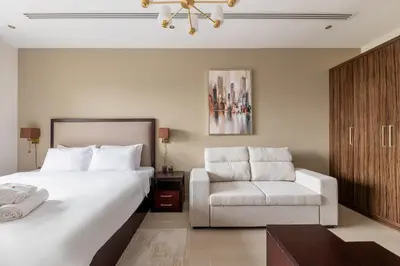 a bedroom with a large bed and a chair at Elite Downtown Studio with Balcony & Pool in Dubai