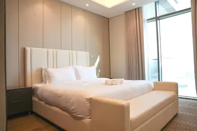 a bedroom with a bed with a chair and a window at Well-Designed Modern 2 BHK Apartment Nobles Tower in Dubai