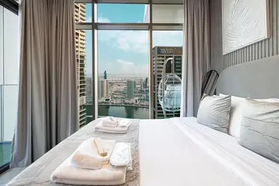 a bedroom with a white bed with a large window at High Rise Premium 2BR apt, PS5, Burj Khalifa view. in Dubai