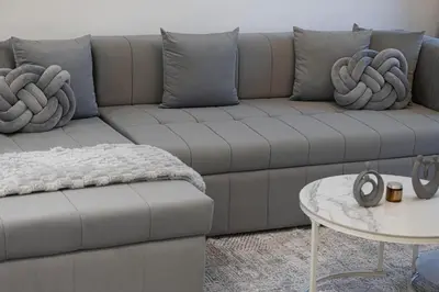 a couch with pillows and a table in a living room at High Rise Premium 2BR apt, PS5, Burj Khalifa view. in Dubai