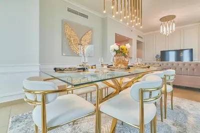 a dining room with a glass table and white chairs at Signature Luxury Apartments Facing Burj Khalifa in Dubai