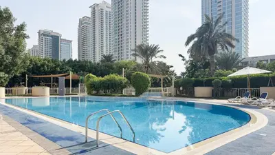 a large swimming pool in a city with tall buildings at Pool View 2BR with Big Balcony in Dubai