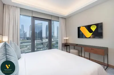 a bedroom with a bed and a desk with a window at Vogue Downtown Address Residence near Burj Khalifa and Dubai Mall, Two Bedroom Apartment with Balcony and Burj Khalifa view, Access to all Amenities in Dubai