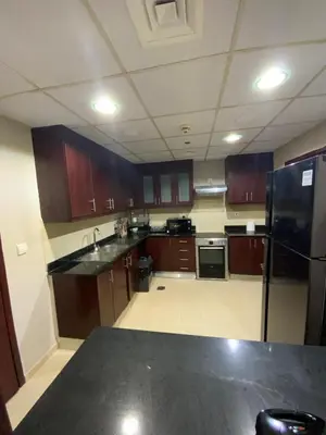 a kitchen with wooden cabinets and a black refrigerator at palm tree Jbr in Dubai