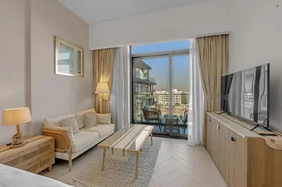 a living room with a couch and a tv at Waves - Boho Style Chic Studio With Balcony in JVC in Dubai