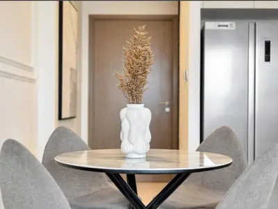 a white vase sitting on a table with chairs at Grand Burj Vista Downtown Apartment with Burj Khalifa View in Dubai