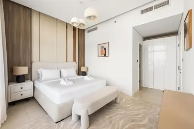 a white bedroom with a white bed and a chair at Elegant 1BR with Pool Gym & Burj Khalifa Views in Dubai