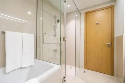 a bathroom with a shower and a glass door at Vogue Downtown Bellevue Towers near Burj Khalifa and Dubai Mall, One bedroom Apartment with Balcony and City view, Access to all Amenities in Dubai