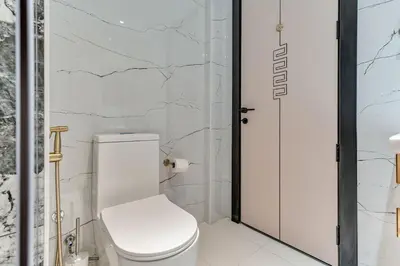 a bathroom with a white toilet and a glass door at Skyz by Danube Chic 2BR with Balcony & Pool Access in Dubai
