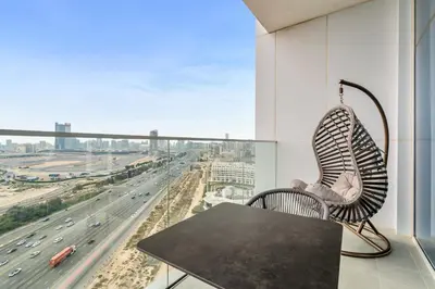 a chair and table on a balcony with a highway at Skyz by Danube Chic 2BR with Balcony & Pool Access in Dubai