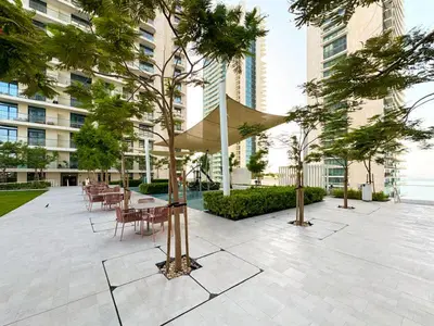 a patio with tables and trees in a building at Modern 1BR with Palm View Dubai Harbour in Dubai