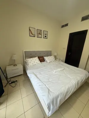 a large white bed in a room with at Modern 1BR in JVC, 2 Baths, Pool & Gym, Fully Equipped Kitchen in Dubai