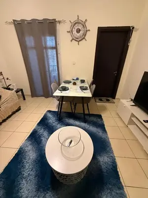 a living room with a table and a blue rug at Modern 1BR in JVC, 2 Baths, Pool & Gym, Fully Equipped Kitchen in Dubai