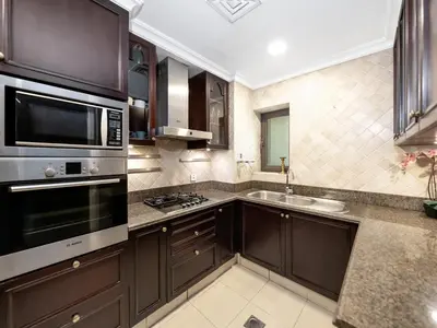 a kitchen with brown cabinets and a microwave and a sink at Skyline Select 1 Bedroom Apartment I Burj Khalifa View I Souk Al Bahar Downtown I Parking, Gym, Wi-Fi & Pool in Dubai