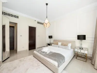 a white bedroom with a large bed and a table at Skyline Select 1 Bedroom Apartment I Burj Khalifa View I Souk Al Bahar Downtown I Parking, Gym, Wi-Fi & Pool in Dubai