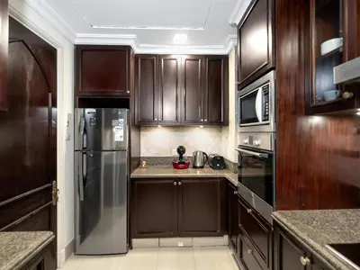 a kitchen with wooden cabinets and a stainless steel refrigerator at Skyline Select 1 Bedroom Apartment I Burj Khalifa View I Souk Al Bahar Downtown I Parking, Gym, Wi-Fi & Pool in Dubai