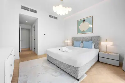 a white bedroom with a large bed with blue pillows at StayShort - Chic Discovery Gardens 1Bed that Sleeps 2 in Dubai