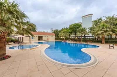a swimming pool with palm trees and a building at StayShort - Chic Discovery Gardens 1Bed that Sleeps 2 in Dubai