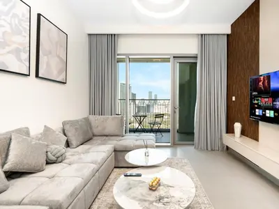 a living room with a couch and a tv at Downtown Dubai 1BR Apartment I Balcony I Dubai Mall Access in Dubai
