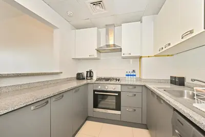 a kitchen with white cabinets and stainless steel appliances at Modern 1BDR Apt With Balcony Pool Access And JVC in Dubai