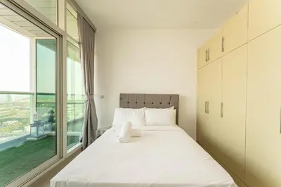 a bedroom with a bed and a large window at HAVN - 2 bed in Hilliana Tower, Jumeirah Burj View in Dubai